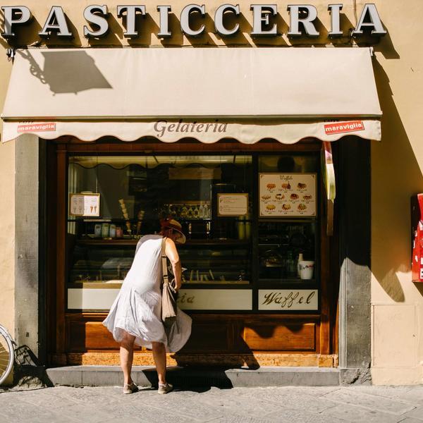 The image shows a person in front of an ice cream shop (Gelateria) in Lucca, Italy.