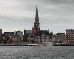 Photo by Deyaar Rumi on pexels.com The image shows the Aarhus seafront, including boats, houses and a church.