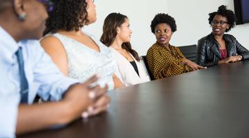 5 people sitting at a table, having a conversation.