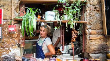 Photo by Yoav Aziz on Unsplash The image shows a person selling agri-food products through a small window that is decorated with plants.